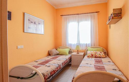 La FloridaにあるNice Home In La Florida With 2 Bedrooms And Wifiのオレンジ色の壁と窓が備わる客室で、ベッド2台が付いています。