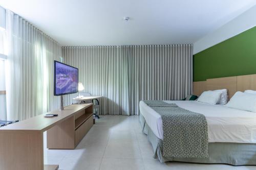 a hotel room with a bed and a flat screen tv at Sotero Hotel by Castelo Itaipava in Salvador