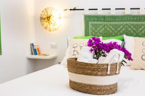 a basket of towels and purple flowers on a bed at Le Maschere B&B in Santa Teresa Gallura
