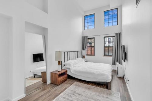 a white bedroom with a bed and a mirror at Stylish 2BR Loft - Carroll Gardens - Prime area in Brooklyn