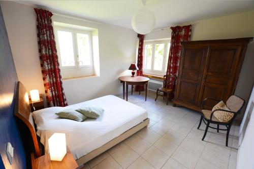 une chambre avec un lit et une table et deux fenêtres dans l'établissement Les Bardilles - dans la campagne à 3 km de SARLAT, à Sarlat-la-Canéda