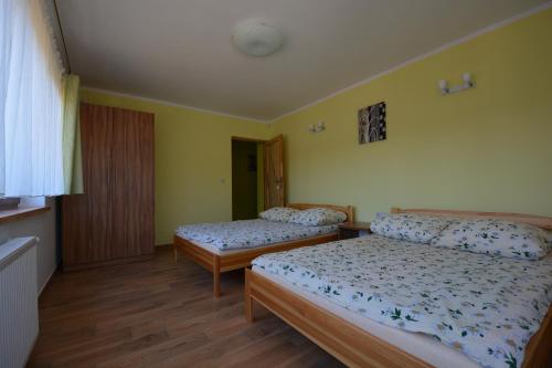 two beds in a room with yellow walls and wooden floors at Domyletnie Sarbinowo 8e dom 86m2 z ogrodzoną działką in Sarbinowo