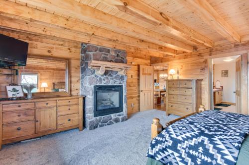 a bedroom with a fireplace in a log cabin at Spacious Howard Cabin with Wraparound Deck and Views! 