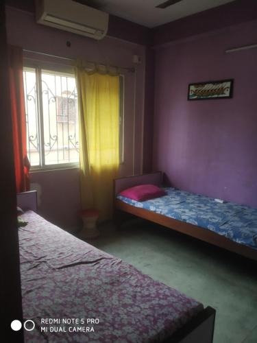 a bedroom with two beds and a window at Gouri Bhawan in Kolkata