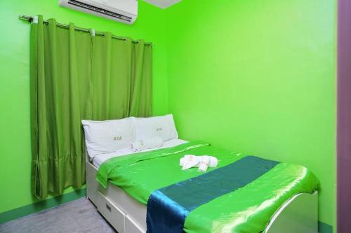 um quarto verde com uma cama com um cão branco em Golden V Executive Homes Unit I em Malolos
