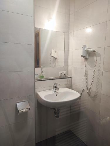 a white bathroom with a sink and a phone at Wirtshaus Zur Bina in Vilsbiburg