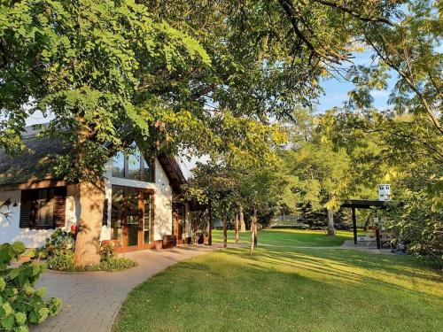 a building with a tree next to a park at Cottage1 in Nature Resort Swimming Pond Pool Sauna in Kiskunmajsa