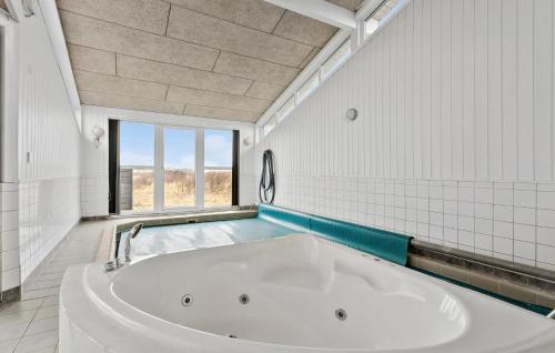 ロンストラップにあるNice Home In Hjrring With Saunaの窓付きのバスルーム(大きな白いバスタブ付)