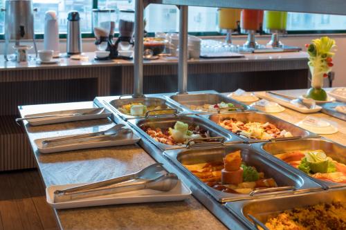 a buffet with several trays of food on a table at Sotero Hotel by Castelo Itaipava in Salvador