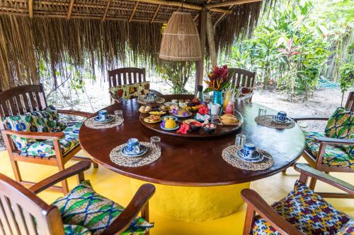 una mesa con comida en una habitación con sillas en Pousada Canoa Nativa, en Isla de Boipeba
