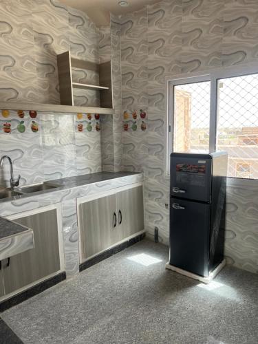 a kitchen with a sink and a refrigerator at Résidence Mounir in Thiès