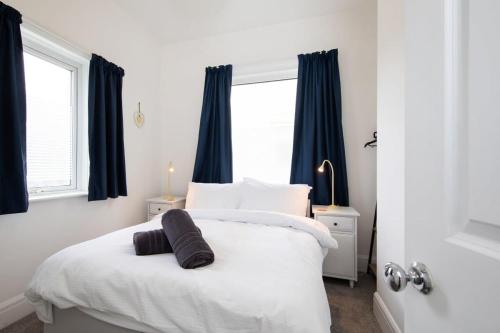 a bedroom with a white bed with black curtains at Absolute Beachfront with Decked Garden Oasis and Views in Bognor Regis