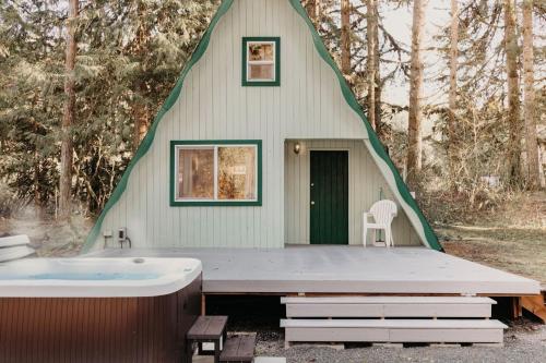 uma banheira sentada em frente a um edifício triangular com uma árvore em 54SL - Hot Tub - Pets OK - Sleeps 4 cabin em Glacier