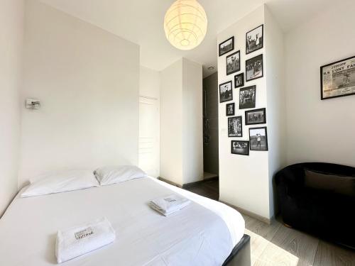 - une chambre avec un lit blanc et des photos sur le mur dans l'établissement LE MIDOU - Vue Rivière, à Mont-de-Marsan