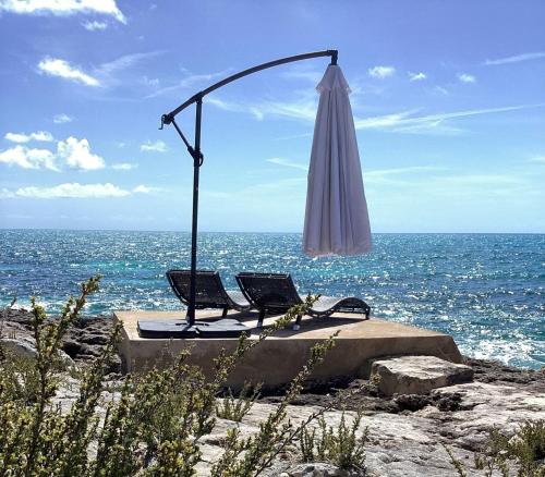 una sombrilla y dos sillas en la playa con el océano en Ocean Shire home, en Alice Town