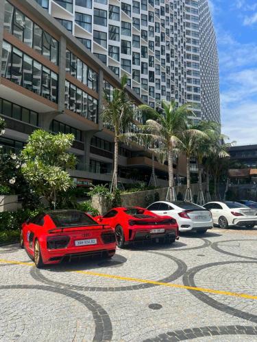 two red cars parked in a parking lot in front of a building at APEC MANDALA Condotel in Phan Thiet