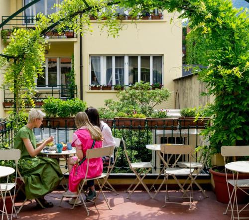trzy osoby siedzące przy stole na patio w obiekcie Ostello Bello Lake Como w Como