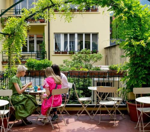 tres personas sentadas en una mesa en un patio en Ostello Bello Lake Como, en Como