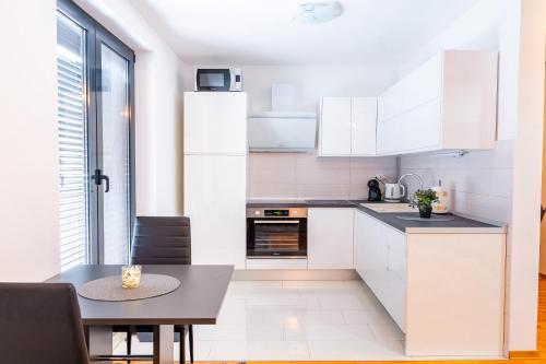 a kitchen with white cabinets and a dining table at Apartman Centar,self check IN-OUT in Županja