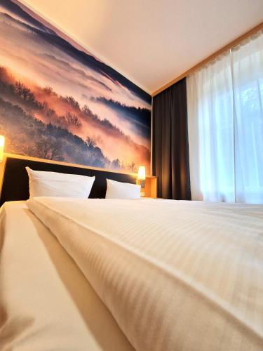 a bedroom with a large bed with a painting on the wall at Hotel Lindenhof Bad Schandau in Bad Schandau