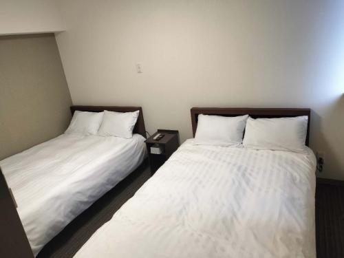 2 Betten nebeneinander in einem Zimmer in der Unterkunft FLYCAT INN 伊勢 in Ise