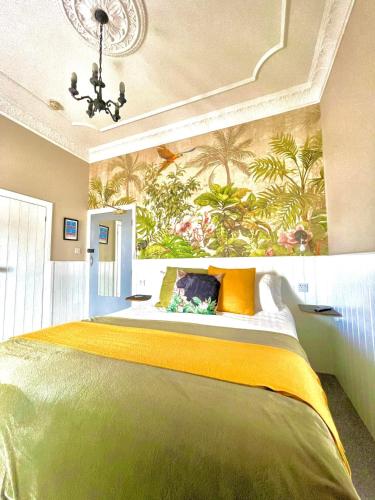 een slaapkamer met een groot groen bed en een muurschildering bij No: 1 The Esplanade Guest Accommodation. in Tenby