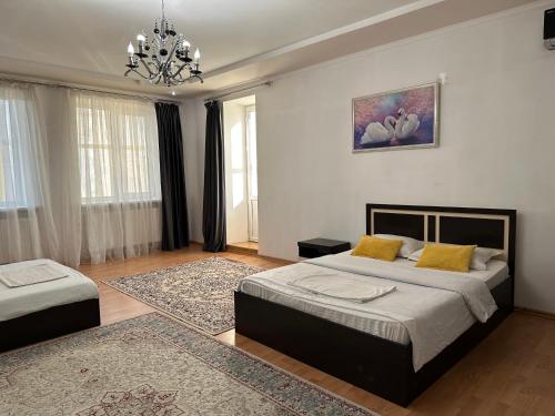 1 dormitorio con 2 camas y lámpara de araña en Уютная и просторная 3х комнатная в ЦЕНТРЕ, en Uralsk