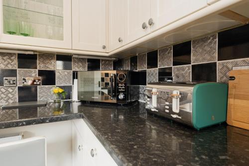 a kitchen with black and white tiles on the wall at Chester Greenway House - Ideal 1 Bedroom Home, EV Charger & Parking - Sleeps 4 in Chester