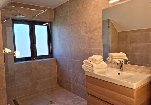 La salle de bains est pourvue d'un lavabo, d'une douche et de serviettes. dans l'établissement Cottage im Natur-Resort Pool, Schwimmteich & Sauna, à Kiskunmajsa