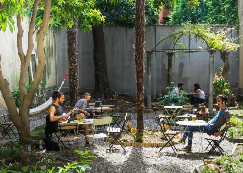 a group of people sitting at tables in a garden at Ostello Bello Lake Como in Como