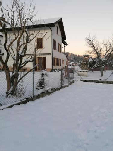 a snow covered yard with a house and a fence at La capucine in Sonvilier