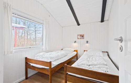 two beds in a room with a window at Amazing Home In Oksbl With 3 Bedrooms And Wifi in Oksbøl