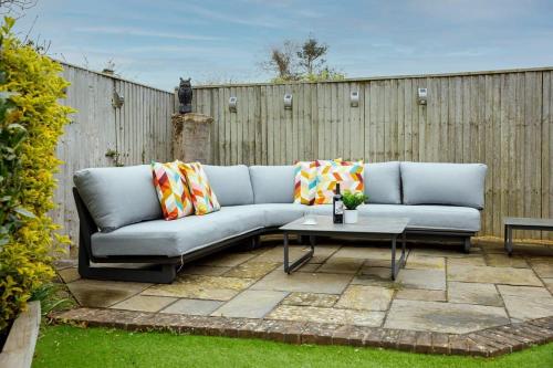 a couch sitting on a patio with a table at Modern & stylish seaside family home in Chichester