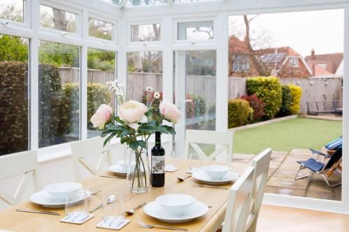 a dining room with a table with pink roses on it at Modern & stylish seaside family home in Chichester