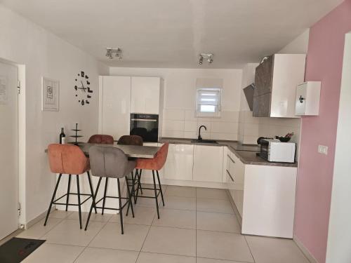 a kitchen with white cabinets and a table and stools at Split/Podstrana Apartment ADRIA in Podstrana