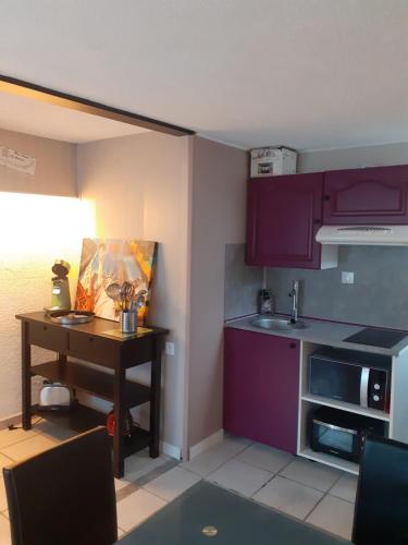 une petite cuisine avec des placards violets et une table dans l'établissement Manhattan, à Villard-de-Lans
