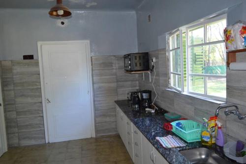 eine Küche mit einer Theke, einem Waschbecken und einem Fenster in der Unterkunft Casa Quinta El Romance 5100m2 in La Reja