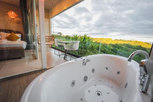 a bathroom with a tub and a balcony with a bed at Kirin Sky Resort in Khao Kho