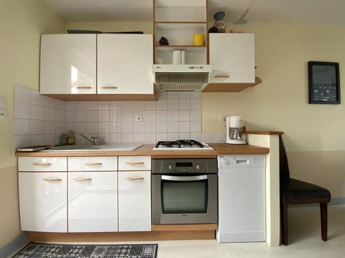 une cuisine avec des armoires blanches et un four à plaques de cuisson dans l'établissement 659 - Charmante maison en pierres, dans le centre d'Erquy,, à Erquy