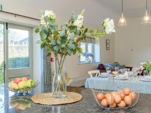 a vase with flowers and fruit on a table at Tull in Dyrham