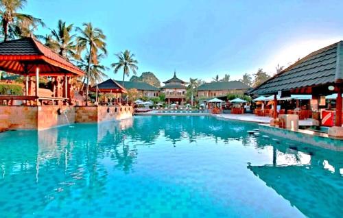 a swimming pool at a resort with blue water at Suite Hotel Apartment Legian by RCP in Seminyak