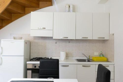 La cuisine est équipée de placards blancs et d'un réfrigérateur blanc. dans l'établissement [Appartamento Duomo], à Tortone