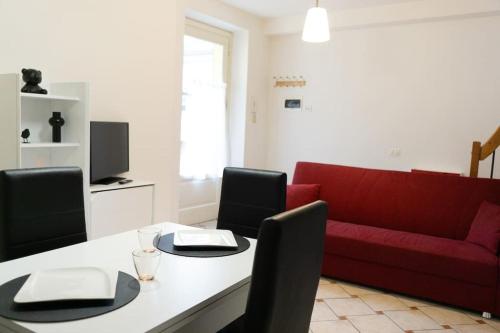 un soggiorno con divano rosso e tavolo di [Appartamento Duomo] a Tortona