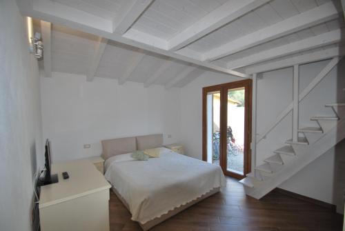 a white bedroom with a bed and a staircase at Villetta Orchidea - Indipendente con giardino privato in Marina di Campo