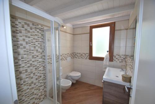 a bathroom with a toilet and a sink and a shower at Villetta Orchidea - Indipendente con giardino privato in Marina di Campo