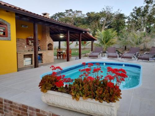 a pool with red flowers in a planter next to a house at Pouso Zen in Araruama