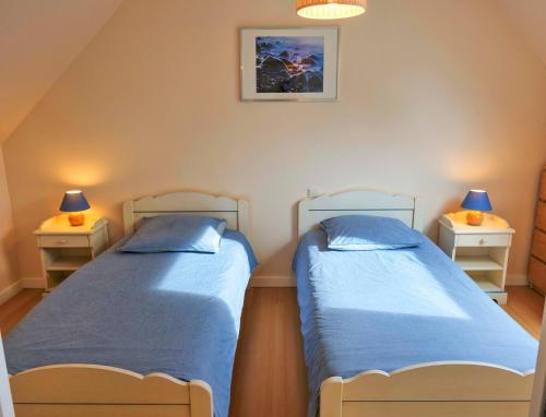 two beds in a room with two night stands at Maison près de la plage et de la thalasso in Roscoff