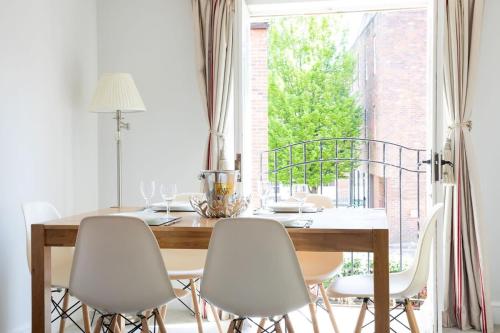 Central Chichester 3bd Mews House For Up To 6 في شيشستر: طاولة طعام مع كراسي بيضاء ونافذة