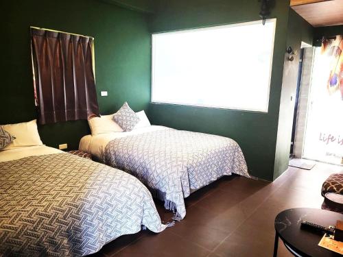 a bedroom with two beds and a green wall at 台東 夢之谷 l 寵物友善 l 停車場 in Taitung City