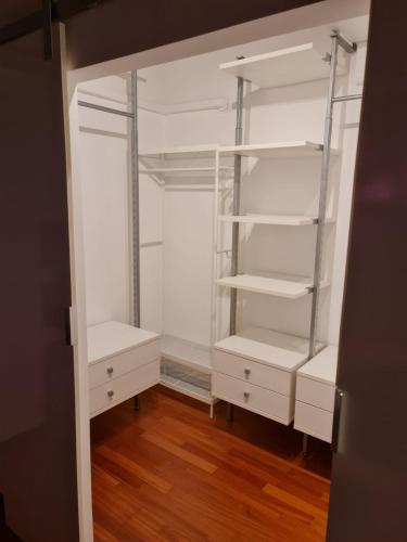 an empty closet with white shelves and wooden floors at Casa Camilla in Certosa di Pavia